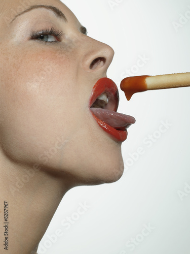Photo: Close-up of a young woman eating a breadstick with sauce Close-up of a young woman eating a breadstick with sauce