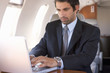 A businessman using a laptop in a plane
