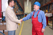 manager and older worker hanshake in warehouse