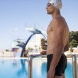 A young man standing by a swimming pool
