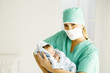 A medical practitioner holding a newborn baby