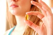 blond woman holding vitamin capsule between finger and thumb blond woman holding vitamin capsule between finger and thumb