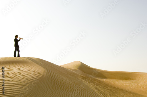 Photo: A young man standing in the desert with a loud hailer A young man standing in the desert with a loud hailer