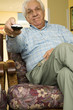 An elderly man using a TV remote control