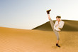 A young woman kick boxing in the desert