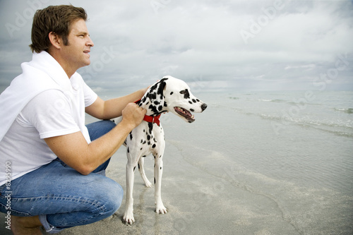 Photo: A man with his dog on a beach A man with his dog on a beach
