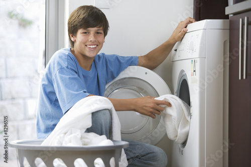 Photo: A young boy loading the washing machine A young boy loading the washing machine
