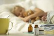 Photo: Close-up of a cup with medicine bottles on a table and a girl sleeping on the bed in the background Close-up of a cup with medicine bottles on a table and a girl sleeping on the bed in the background