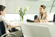 A receptionist greeting a woman in a wheelchair