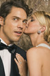 Side profile of a young woman whispering to a young man