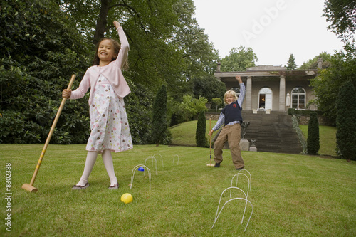 Photo: Boy and girl playing croquet in a garden Boy and girl playing croquet in a garden