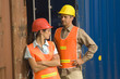 Two dock workers standing in front of cargo containers
