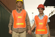 Photo: Portrait of two dock workers holding each other's hands and smiling at a commercial dock Portrait of two dock workers holding each other's hands and smiling at a commercial dock