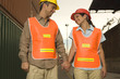 Two dock workers holding each other's hands and smiling at a commercial dock