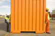 Photo: Male dock worker hiding from a businessman behind a cargo container at a commercial dock Male dock worker hiding from a businessman behind a cargo container at a commercial dock