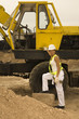 Female construction worker standing by an earth mover