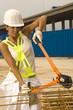 Female dock worker cutting iron rods with a bolt cutter