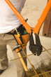 Photo: Low section view of a male construction worker cutting iron rods with a bolt cutter Low section view of a male construction worker cutting iron rods with a bolt cutter