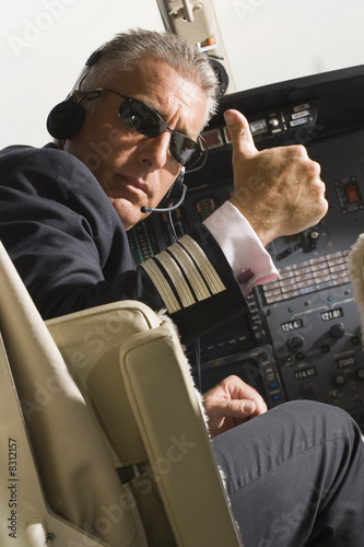 Photo: Pilot making thumbs up sign in the cockpit of a private airplane Pilot making thumbs up sign in the cockpit of a private airplane