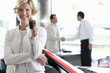 Photo: Salesman shaking hands with customer in car showroom, focus on woman with key, smiling, portrait Salesman shaking hands with customer in car showroom, focus on woman with key, smiling, portrait