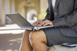 Photo: Businesswoman, in grey suit, using laptop in buiding arcade, side view, mid-section Businesswoman, in grey suit, using laptop in buiding arcade, side view, mid-section