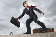 Businessman with briefcase standing on windy ledge