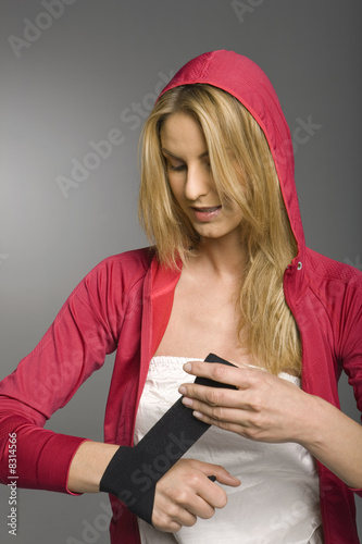 Photo: Young woman wrapping injured wrist, studio shot Young woman wrapping injured wrist, studio shot