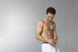 Young man wearing towel measuring waist