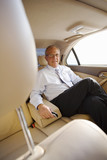 Photo: Senior businessman sitting in back-seat of car, leaning arm rest, smiling, portrait Senior businessman sitting in back-seat of car, leaning arm rest, smiling, portrait