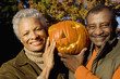 Photo: Senior couple holding aloft Jack O'Lantern pumpkin, smiling, front view, close-up, portrait Senior couple holding aloft Jack O'Lantern pumpkin, smiling, front view, close-up, portrait