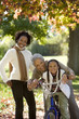 Photo: Girl (7-9) sitting on bicycle beside mother and grandmother in autumn park, senior woman embracing granddaughter, portrait Girl (7-9) sitting on bicycle beside mother and grandmother in autumn park, senior woman embracing granddaughter, portrait