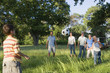 Photo: Multi-generational family playing with soccer ball in woodland clearing on camping trip Multi-generational family playing with soccer ball in woodland clearing on camping trip