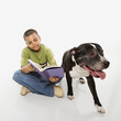 Boy reading book with dog.