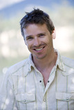 Photo: Man wearing white shirt with open collar, smiling, close-up, front view, portrait Man wearing white shirt with open collar, smiling, close-up, front view, portrait