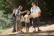 Photo: Boy (8-10) hiking on woodland trail with father and grandfather, man consulting map, smiling Boy (8-10) hiking on woodland trail with father and grandfather, man consulting map, smiling