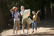 Photo: Girl (7-9) hiking on woodland trail with mother and grandmother, pointing, woman consulting map, smiling Girl (7-9) hiking on woodland trail with mother and grandmother, pointing, woman consulting map, smiling