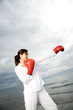 A woman wearing boxing gloves on a beach