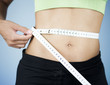 A young woman measuring her waist