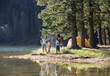 Photo: Family, in mid-distance, fishing beside lake on camping trip, woman holding catch, man with fishing rod Family, in mid-distance, fishing beside lake on camping trip, woman holding catch, man with fishing rod