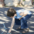 Young boy writing in chalk on the playground
