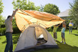 Photo: Father assembling dome tent with children (8-10) on garden lawn, grandmother serving drinks in background, smiling Father assembling dome tent with children (8-10) on garden lawn, grandmother serving drinks in background, smiling