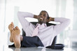 Businessman sitting in office with feet on desk relaxing and smi
