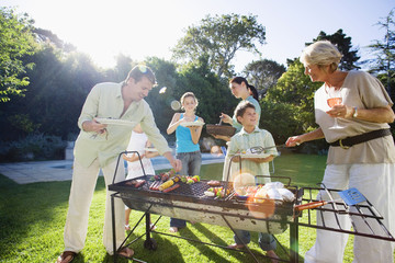 Photo: Family having barbecue in summer garden, senior woman serving grandson (8-10), man taking kebab from grill, smiling (lens flare) Family having barbecue in summer garden, senior woman serving grandson (8-10), man taking kebab from grill, smiling (lens flare)