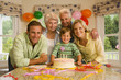 Photo: Three generation family celebrating birthday at home, boy (4-6) sitting beside birthday cake, smiling, portrait Three generation family celebrating birthday at home, boy (4-6) sitting beside birthday cake, smiling, portrait