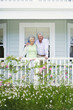 Photo: Senior couple standing on veranda overlooking summer garden, arms around each other, smiling, front view, portrait Senior couple standing on veranda overlooking summer garden, arms around each other, smiling, front view, portrait