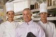 Photo: Restaurant manager standing with male and female chefs in commercial kitchen, smiling, front view, portrait Restaurant manager standing with male and female chefs in commercial kitchen, smiling, front view, portrait