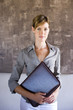 Photo: Female manager standing in restaurant, holding menu, smiling, front view, portrait Female manager standing in restaurant, holding menu, smiling, front view, portrait