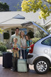 Photo: Family standing with luggage beside open boot of parked car on driveway, boy (8-10) holding teddy bear, smiling, portrait Family standing with luggage beside open boot of parked car on driveway, boy (8-10) holding teddy bear, smiling, portrait