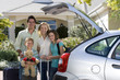 Photo: Family standing with luggage beside open boot of parked car on driveway, boy (8-10) holding teddy bear, smiling, portrait Family standing with luggage beside open boot of parked car on driveway, boy (8-10) holding teddy bear, smiling, portrait