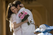 Photo: Couple embracing beside parked motor scooter near colonnade, woman holding bouquet of pink flowers, smiling Couple embracing beside parked motor scooter near colonnade, woman holding bouquet of pink flowers, smiling
